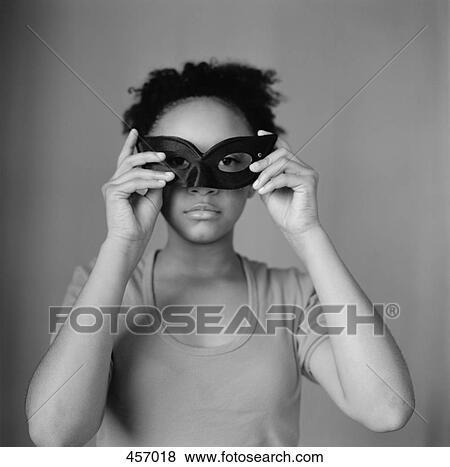 Girl holding a mask to her face View Large Photo Image Stock Photo - Girl holding a mask to her face. Fotosearch