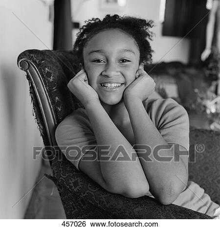 Stock Photograph - Teenage girl sitting in a chair smiling. Fotosearch