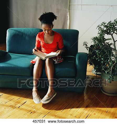 Teenage girl sitting on sofa reading View Large Photo Image Stock Image - Teenage girl sitting on sofa reading. Fotosearch