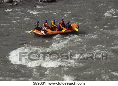 Stock Image - Group of people white water rafting on rapids. Fotosearch