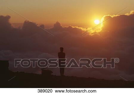 Person standing on a mountain ledge at sunrise View Large Photo Image Stock Image - Person standing on a mountain ledge at sunrise. Fotosearch