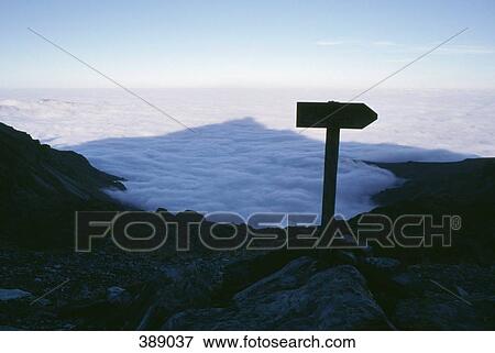 Stock Photo - Shadow of mountain peak over foggy canyon. Fotosearch