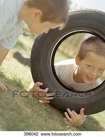 Stock Image - Children playing with tire. Fotosearch