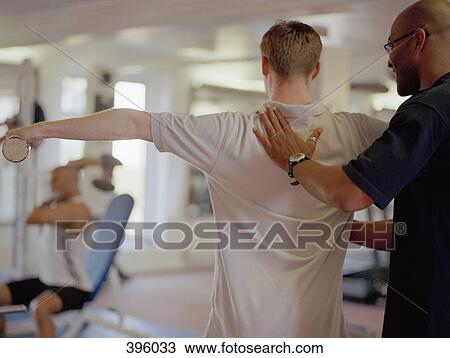 Exercise instructor helping man in gym View Large Photo Image Stock Image - Exercise instructor helping man in gym. Fotosearch