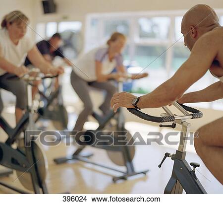 Picture - People using exercise bikes in a gym. Fotosearch