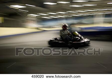 Stock Image - Person driving a go-cart on a race track. Fotosearch