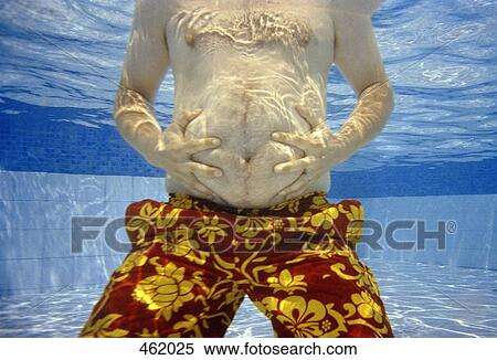 Stock Photography - Midsection of a man holding his belly underwater. Fotosearch
