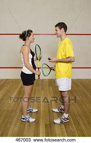 Stock Image - A man and woman standing on a squash court. Fotosearch