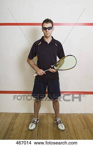 Picture - A man standing on a squash court. Fotosearch