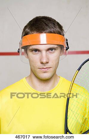 Stock Photo - Portrait of a man wearing a visor and holding a squash racquet. Fotosearch