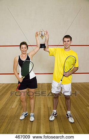 Stock Photo - Two squash team mates holding a trophy. Fotosearch