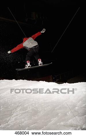 Picture - Snowboarder mid-air on a ski slope. Fotosearch