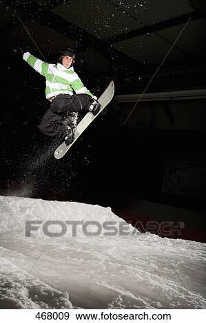 Snowboarder mid-air on a ski slope View Large Photo Image Stock Photo - Snowboarder mid-air on a ski slope. Fotosearch