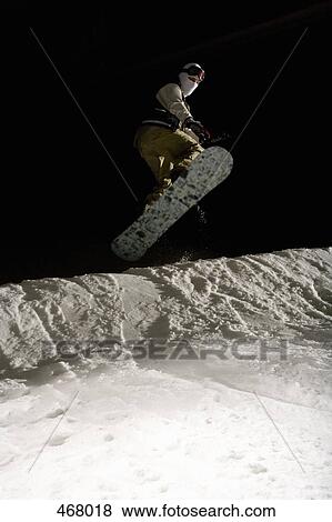 Stock Photo - Snowboarder mid-air on a ski slope. Fotosearch