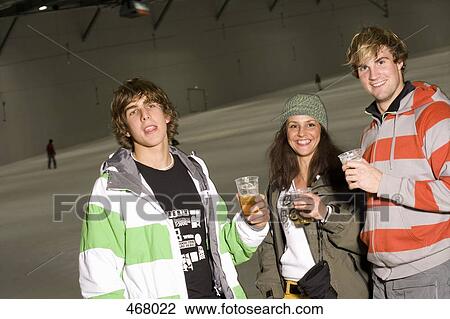 Three friends standing on a ski slope and drinking beer View Large Photo Image Stock Image - Three friends standing on a ski slope and drinking beer. Fotosearch