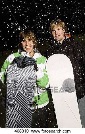 Two young men holding snowboards whilst standing in the snow View Large Photo Image Stock Image - Two young men holding snowboards whilst standing in the snow. Fotosearch
