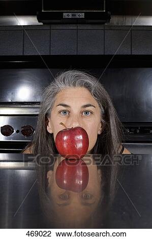 A woman ducking behind a red apple on a kitchen counter View Large Photo Image Stock Image - A woman ducking behind a red apple on a kitchen counter. Fotosearch