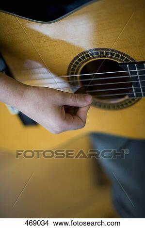 Picture - Detail of a young boy playing an acoustic guitar. Fotosearch