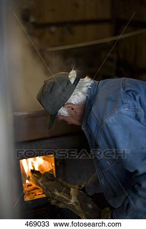 Senior man putting wood into a furnace View Large Photo Image Stock Image - Senior man putting wood into a furnace. Fotosearch