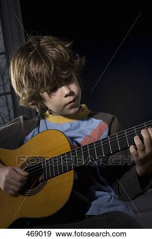 Stock Photo - Young boy playing an acoustic guitar. Fotosearch