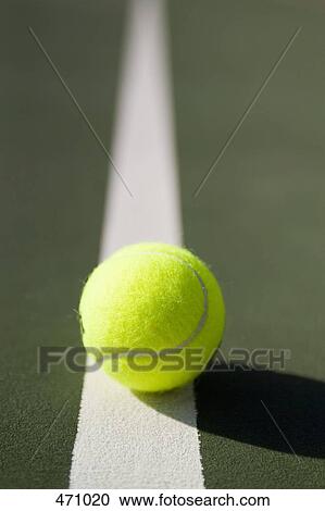 Stock Image - A tennis ball lying on a white line. Fotosearch