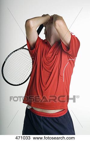 Stock Image - A tennis player covering his face in defeat. Fotosearch