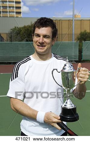 A tennis player holding a trophy View Large Photo Image Stock Image - A tennis player holding a trophy. Fotosearch