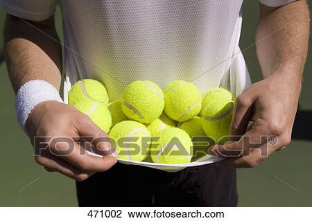 Midsection view of a man carrying tennis balls in his t-shirt View Large Photo Image Stock Image - Midsection view of a man carrying tennis balls in his t-shirt. Fotosearch