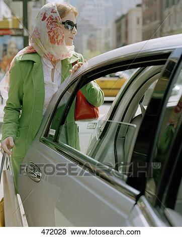 A stylish woman getting into a car View Large Photo Image Stock Photo - A stylish woman getting into a car. Fotosearch