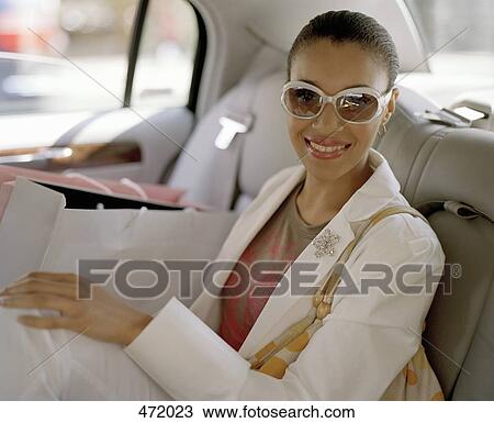 A woman sitting in the back of a taxi with shopping bags View Large Photo Image Stock Image - A woman sitting in the back of a taxi with shopping bags. Fotosearch