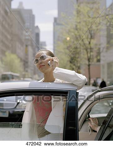 A woman stepping out of a taxi and using a mobile phone, New York City, USA View Large Photo Image Stock Image - A woman stepping out of a taxi and using a mobile phone, New York City, USA. Fotosearch