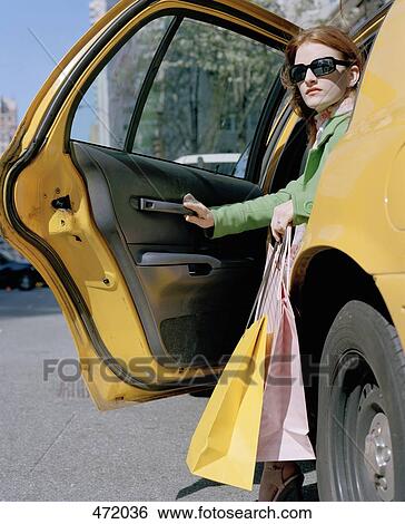 A woman stepping out of a taxi with shopping bags, New York City, USA View Large Photo Image Stock Photograph - A woman stepping out of a taxi with shopping bags, New York City, USA. Fotosearch