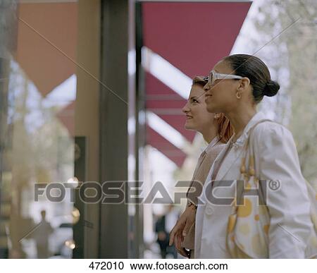 Two woman looking in a shop window View Large Photo Image Stock Image - Two woman looking in a shop window. Fotosearch