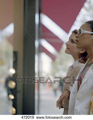 Two woman looking in a shop window View Large Photo Image Stock Photo - Two woman looking in a shop window. Fotosearch