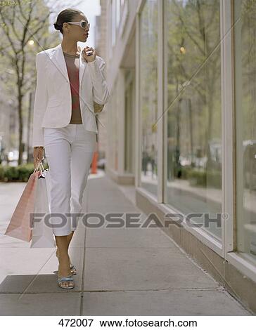 Stock Photo - Woman carrying shopping bags and looking into a shop window. Fotosearch