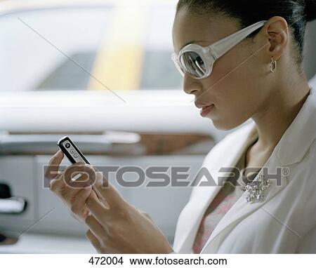 Woman sitting in the back seat of a vehicle and sending a text message View Large Photo Image Picture - Woman sitting in the back seat of a vehicle and sending a text message. Fotosearch