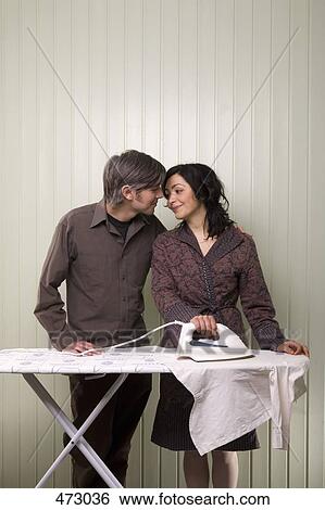 Stock Photograph - A couple kissing whilst ironing. Fotosearch