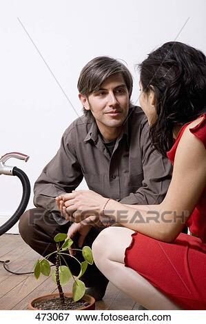 A man and a woman crouching next to a potted plant View Large Photo Image Stock Photo - A man and a woman crouching next to a potted plant. Fotosearch