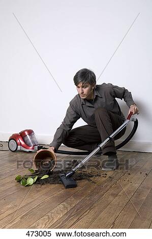 A man vacuuming up soil from a spilt potted plant View Large Photo Image Stock Photography - A man vacuuming up soil from a spilt potted plant. Fotosearch