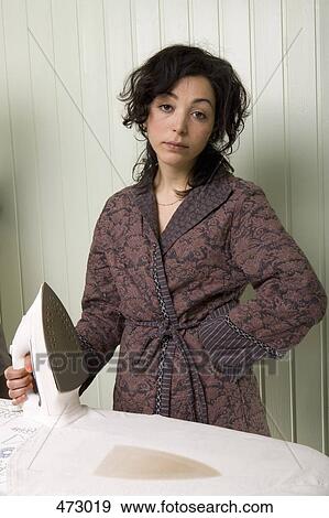 Stock Photo - A woman holding an iron next to a burnt shirt. Fotosearch