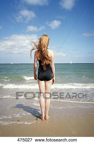 Stock Photo - A woman standing at the edge of the sea. Fotosearch
