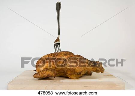 Stock Photo - A fork stuck in a roast chicken. Fotosearch