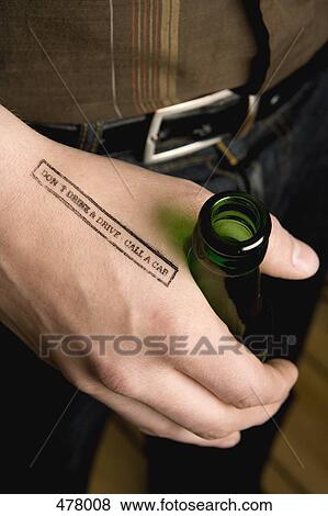 Stock Photo - Close-up of a man holding a beer bottle with a rubber stamp on his hand. Fotosearch