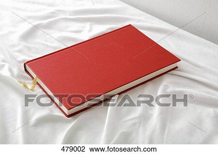 A red book on a bed View Large Photo Image Stock Image - A red book on a bed. Fotosearch