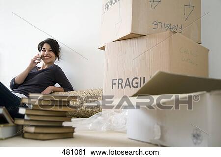 Stock Image - A young woman on the phone in a new house. Fotosearch