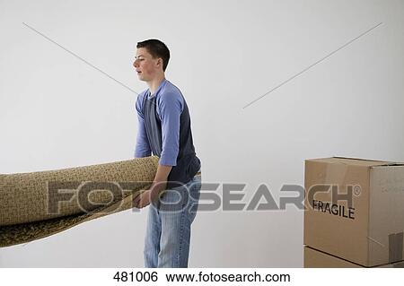 Stock Photograph - Teenage boy carrying a roll of carpet. Fotosearch