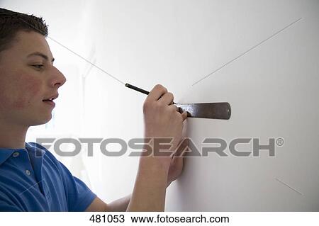 Teenage boy measuring a wall View Large Photo Image Stock Image - Teenage boy measuring a wall. Fotosearch