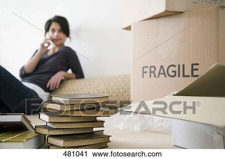 Stock Image - Teenage girl on mobile phone in new house. Fotosearch