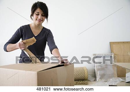 Stock Image - Teenage girl unpacking cardboard boxes. Fotosearch