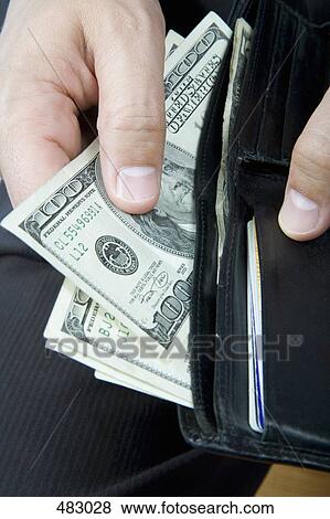 Stock Photo - A businessman taking US bank notes from his wallet. Fotosearch